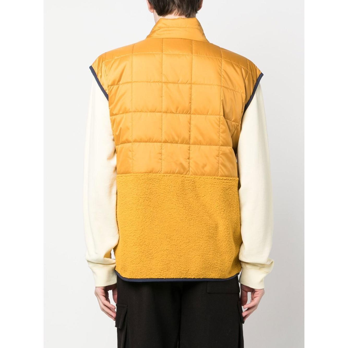 Back view of mustard yellow COTOPAXI padded gilet with a logo patch and trico hybrid design, featuring zip pockets and sleeveless cut.