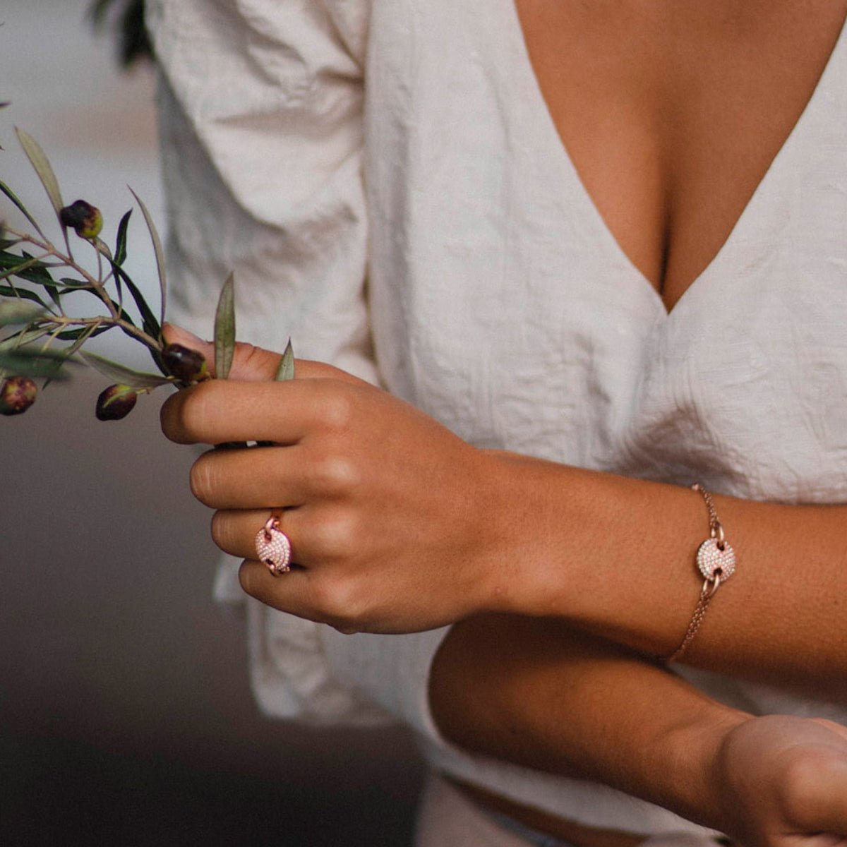 Woman wearing AN JEWELS JEWELRY Mod. AL.BJT01RC ring and bracelet, holding a leafy branch.