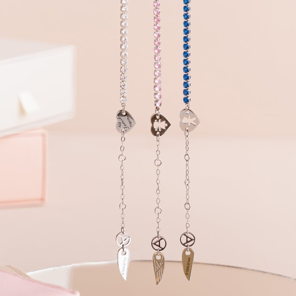 AN JEWELS JEWELRY Mod. AL.BLIYMBL delicate necklaces in silver, pink, and blue hues with unique charm accents displayed elegantly.