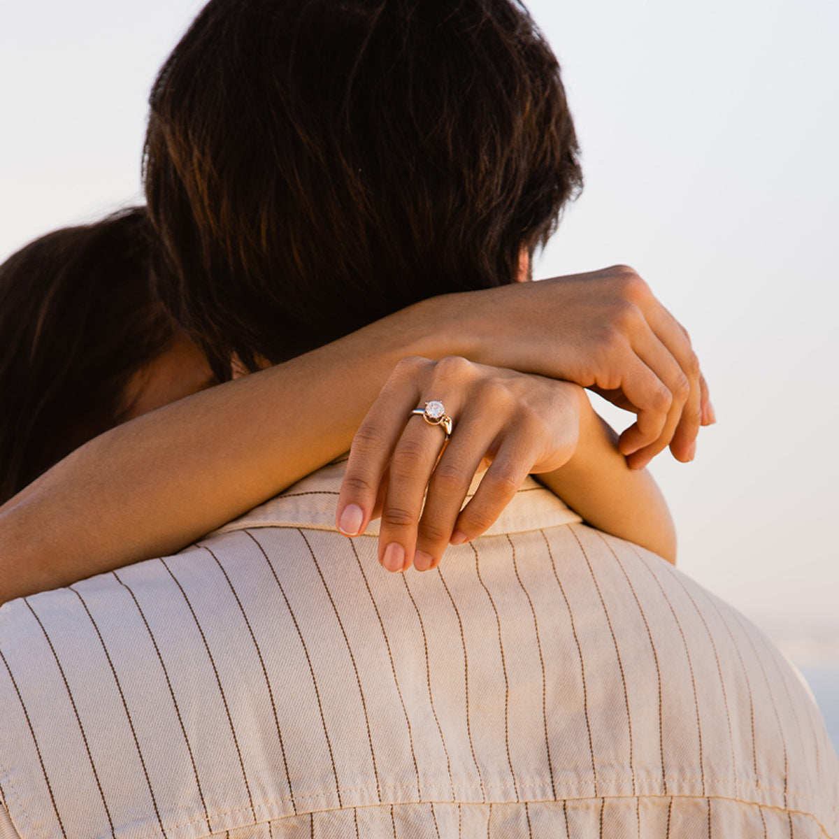 Woman embracing partner showing engagement ring, symbolizing love and commitment.