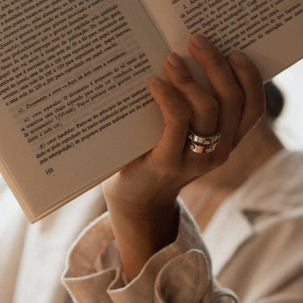 AN JEWELS JEWELRY Mod. AL.RWH01SC-9 ring on hand holding a book, showcasing elegant design and style.