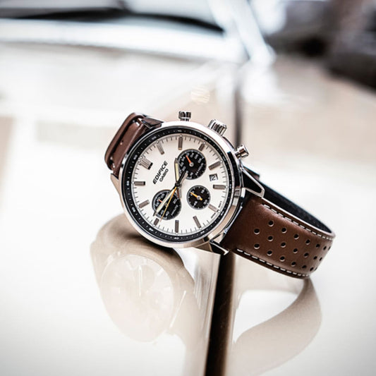 Luxury watch CASIO EDIFICE Mod. STANDARD CHRONOGRAPH - CHAMPAGNE with brown leather strap on reflective surface.