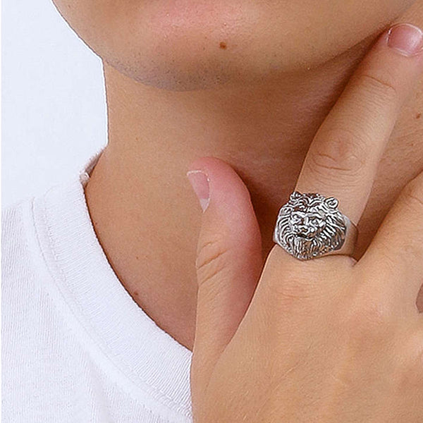 Lion head ring on finger with white shirt background, showcasing intricate details and craftsmanship.