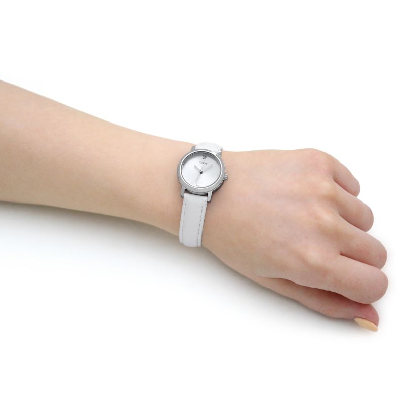 Person wearing a silver analog watch with a white band on their wrist, showcasing a minimalist design.