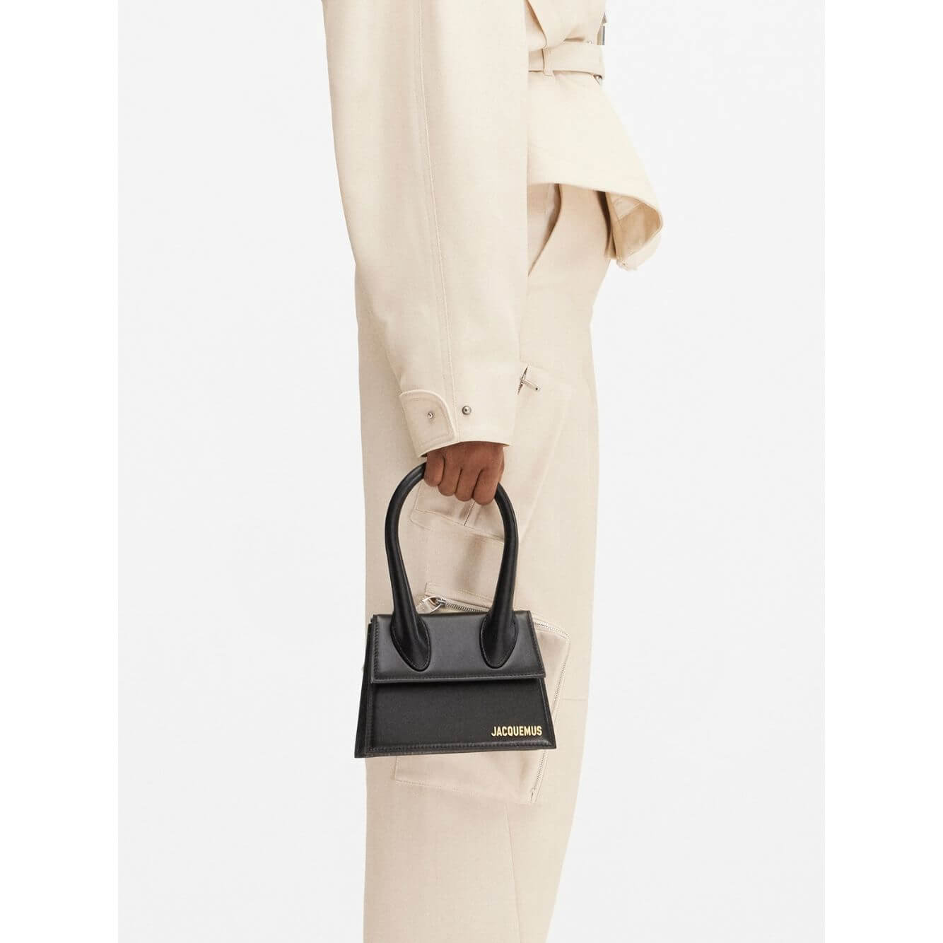 Jacquemus Le Chiquito Moyen Black Bag with gold hardware, shown on model, featuring reinforced handle and magnetic flap closure.