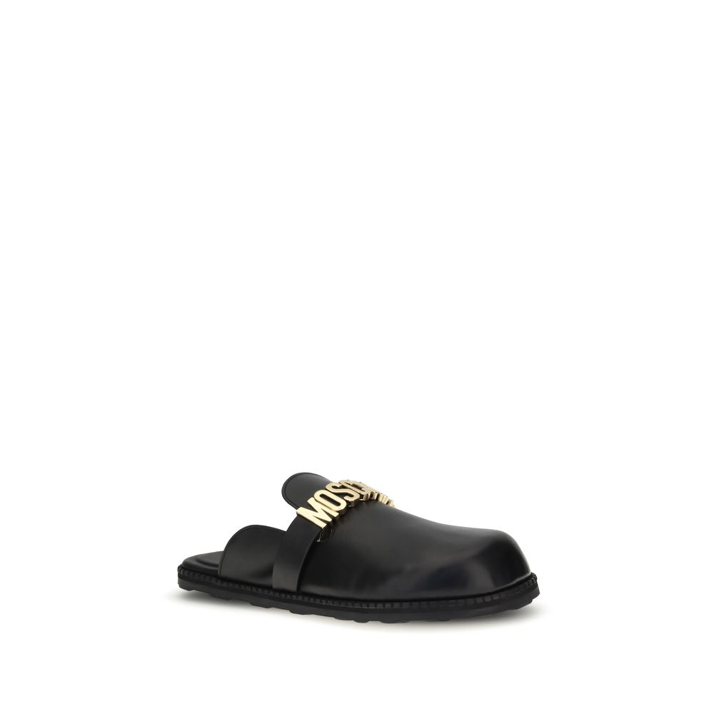 Moschino Black Calf Leather Bos Taurus Mules with gold logo plaque and round toe, perfect for adding a glamorous touch to any outfit.