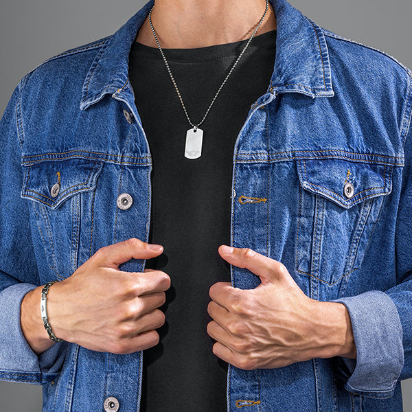 Man wearing POLICE JEWELS JEWELRY Mod. PEAGB0008701 necklace with dog tag, denim jacket, and bracelet