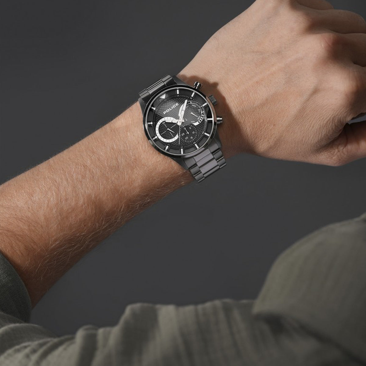 A person wearing POLICE WATCHES Mod. PEWGK0040303M with a dark grey watch face and metal strap, displayed on their wrist.