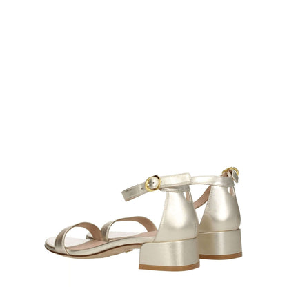 Stuart Weitzman Gold Leather Sandals with buckle closure and mid heels, featuring metallic platinum color and open toe design.