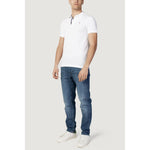 Man wearing Tommy Hilfiger Jeans White Cotton Polo Shirt with jeans and white sneakers showcasing a casual look.