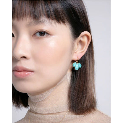 Woman wearing silver earrings with blue gemstones, showcases stylish jewelry fashion on a model.